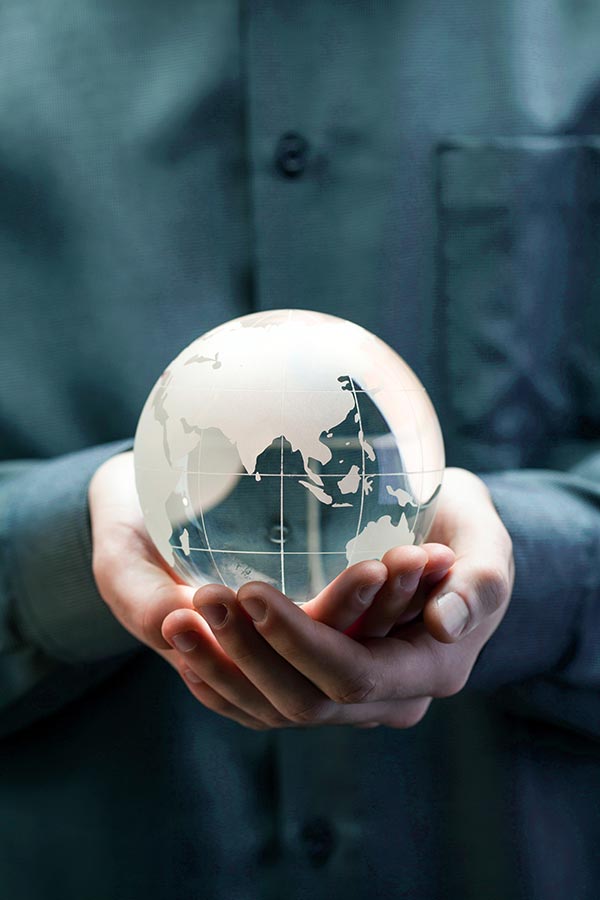 Caring hands of a leader holding a glass globe etched with the world atlas