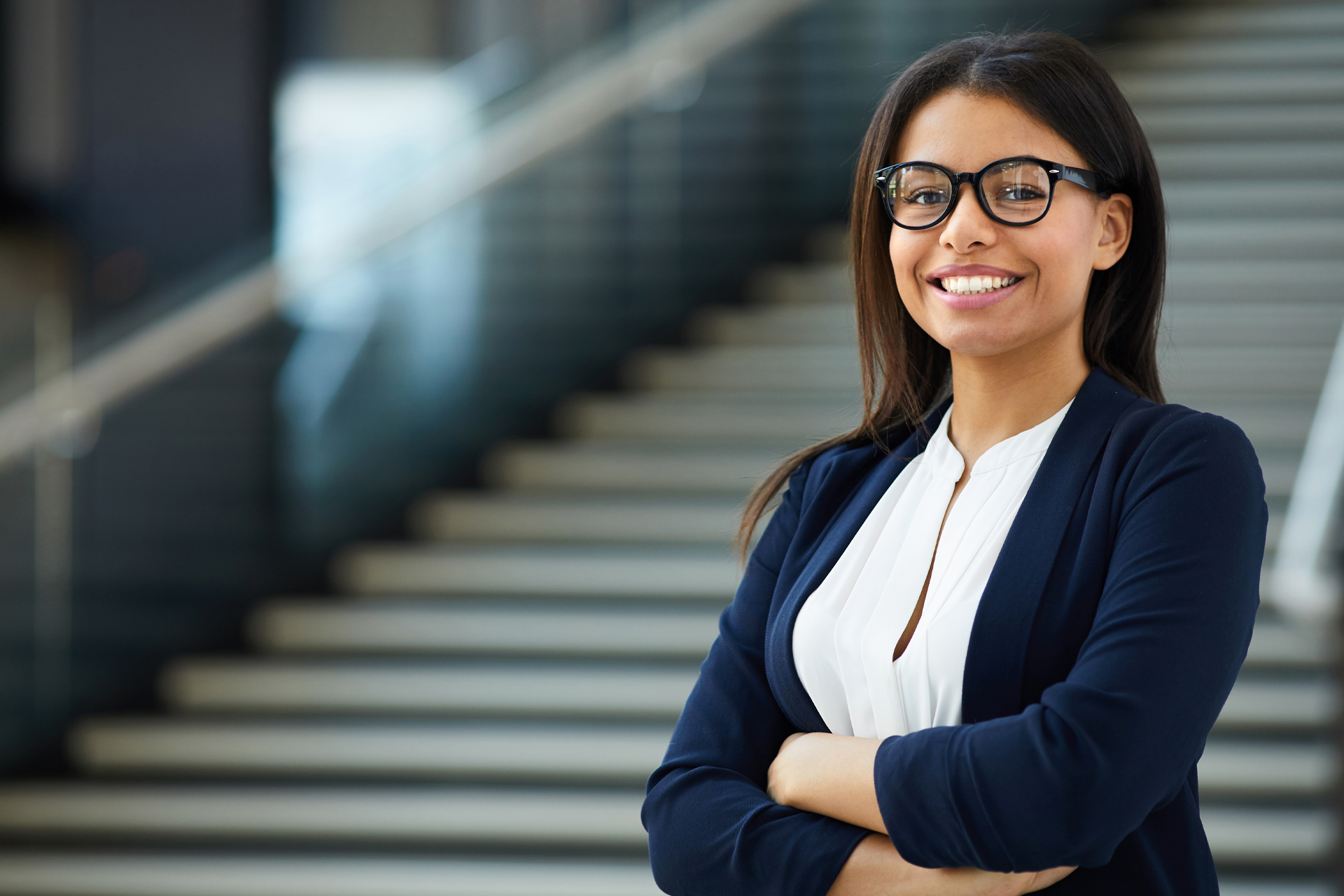 Diverse women entrepreneur standing in front of stairs and smiling at camera.