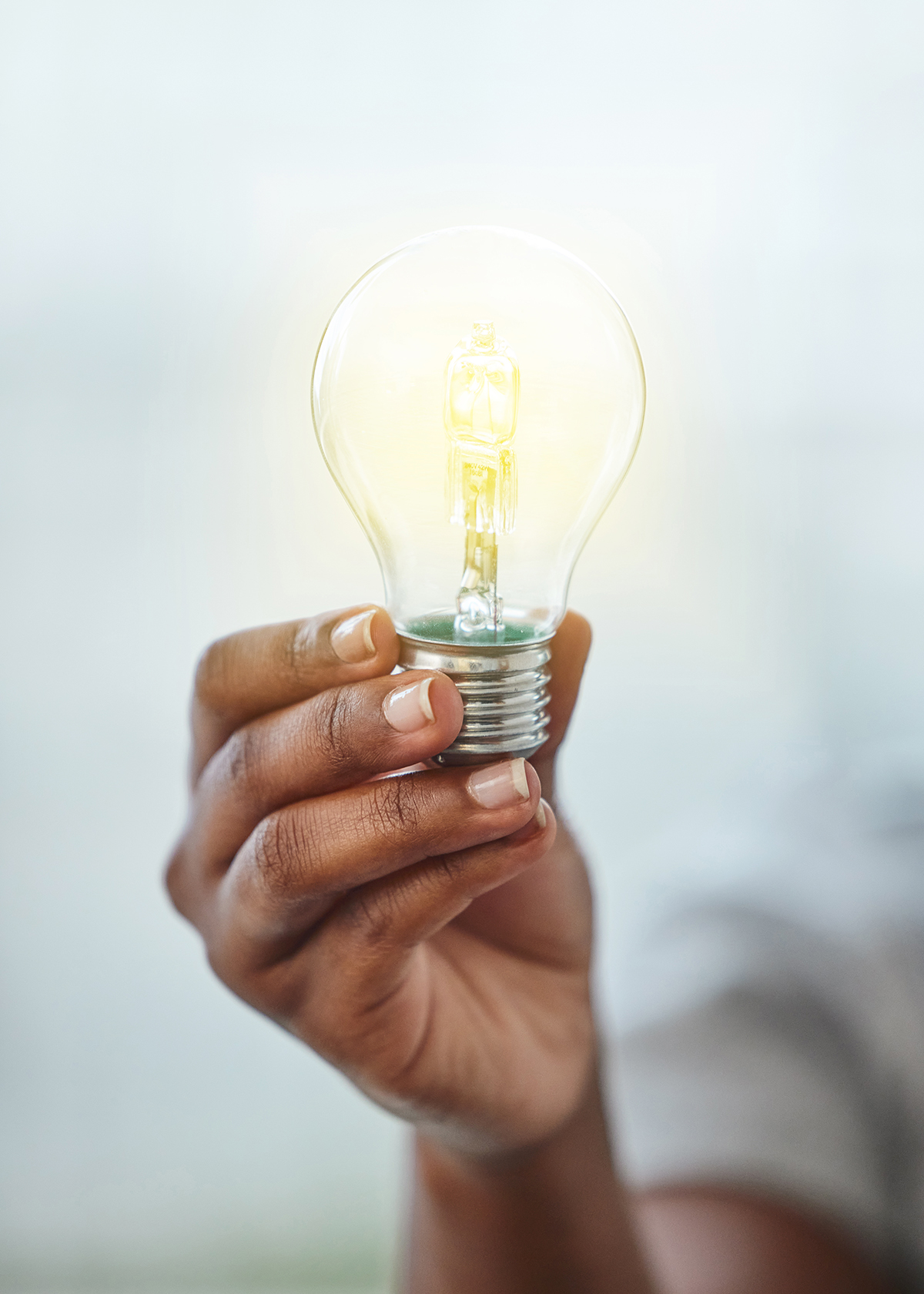 Minority women entrepreneur's hand holding a glowing light bulb representing entrepreneurship coaching